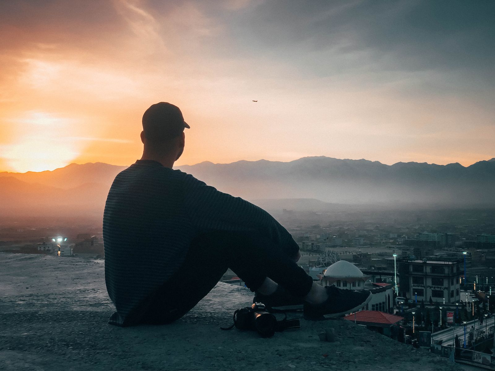A person watching the sunset from a hilltop, a quiet moment of hope